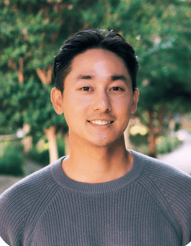 Douglas Lee smiling outdoors among trees